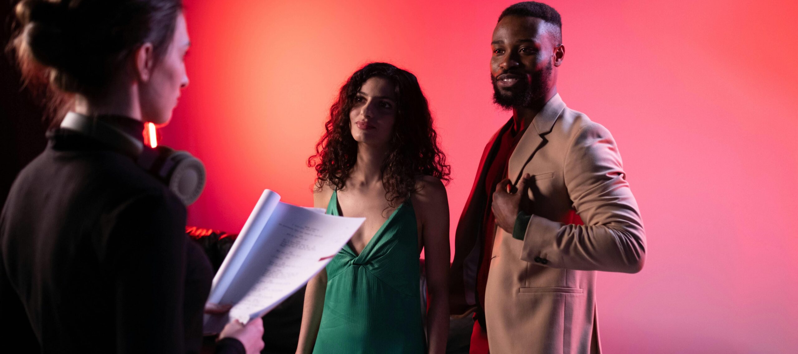 Actors discussing being off-book and script during a studio shoot with dramatic lighting.